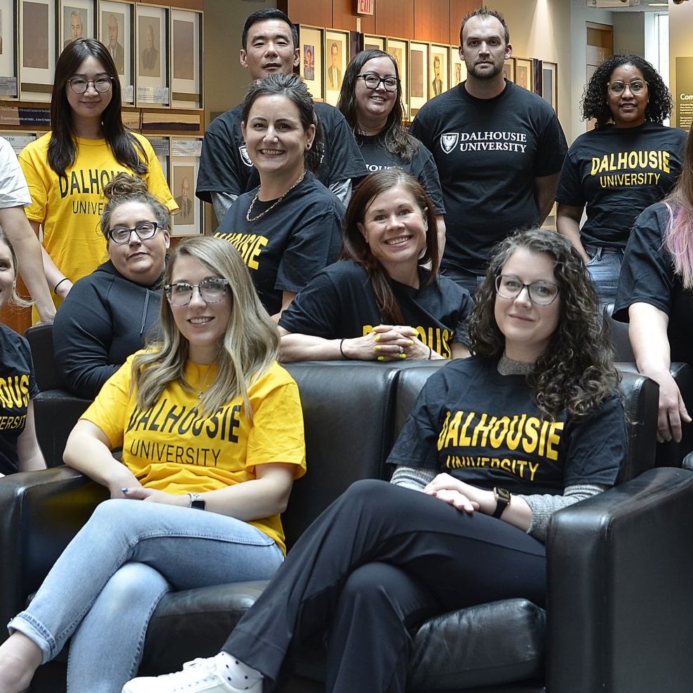 A group of students poses together, each wearing a Dalhousie t-shirt in black, yellow, or white.  