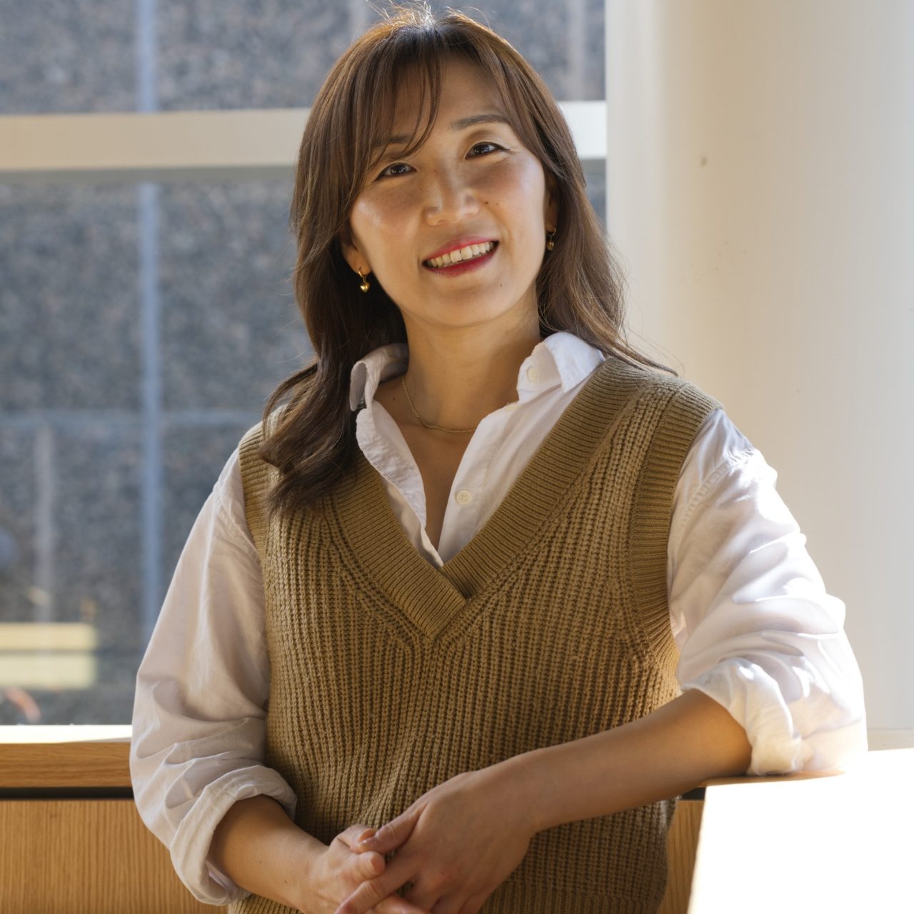 An MI student stands in front of a window with snow visible outside, smiling.