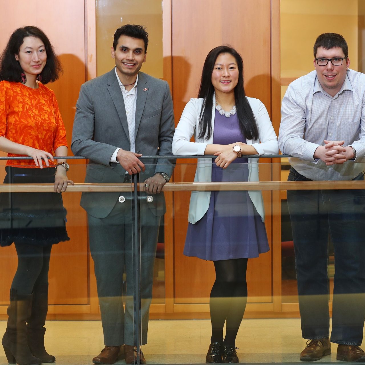Five students lined up against a railing, smiling. 