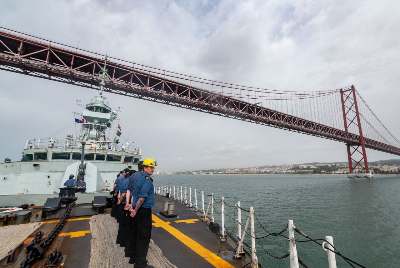 "HMCS HALIFAX passes under The 25 de Abril Bridge during the transit into Lisbon, Portugal as part of Operation REASSURANCE on 21 May 2022.   Please credit: Pte Connor Bennett, Canadian Armed Forces photo ~ Le NCSM HALIFAX passe sous le pont du 25 avril alors qu'il se dirige vers Lisbonne, au Portugal, au cours de l'opération REASSURANCE, le 21 mai 2022.   Photo : Sdt Connor Bennett, Forces armées canadiennes"