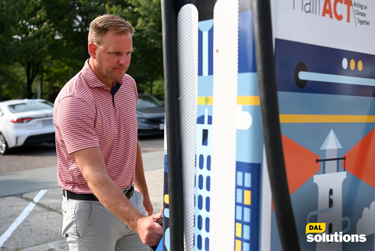 Luke Swan stands next to a fast charger