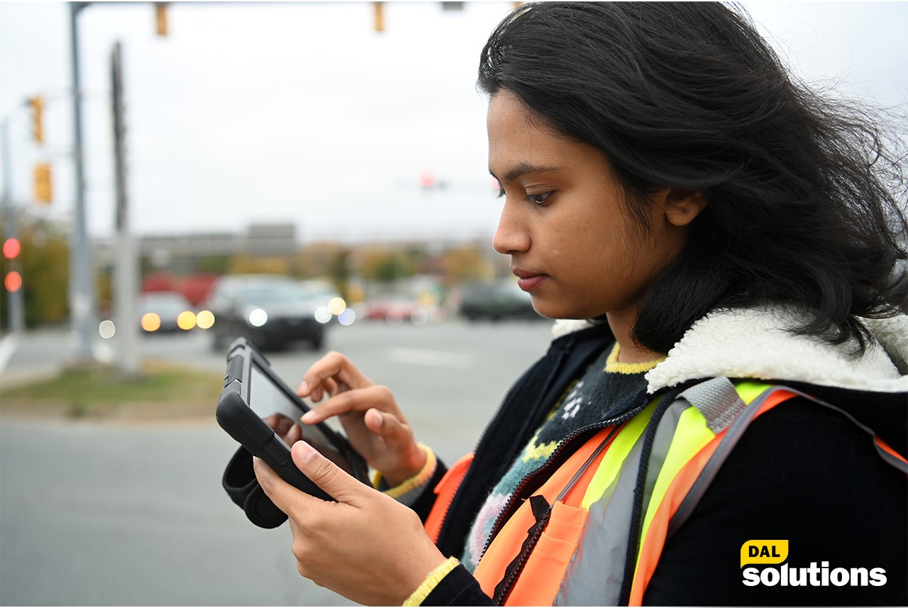 A female student looks at a gadget to collect data from the traffic