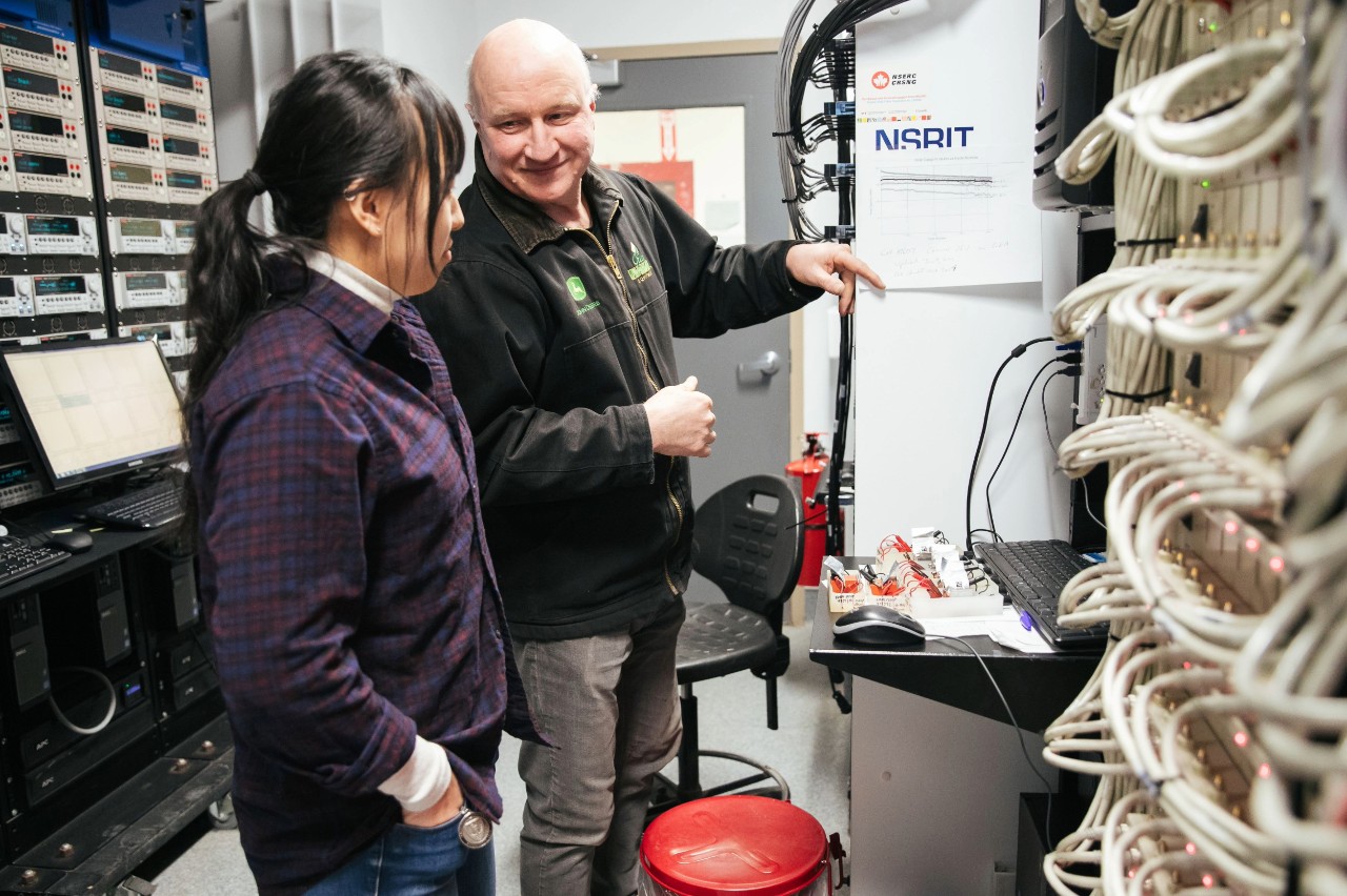Dahn gestures toward equipment in a battery science lab in discussion with another researcher.
