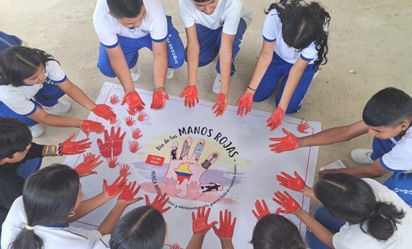 Kids with red print hands pressing on a flag on the ground