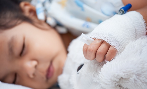 Sick child girl's hand with saline intravenous (iv) drip hugging her doll while sleeping in the hospital