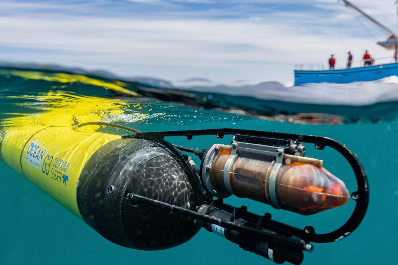 Underwater vehicle near ocean surface with boat in background