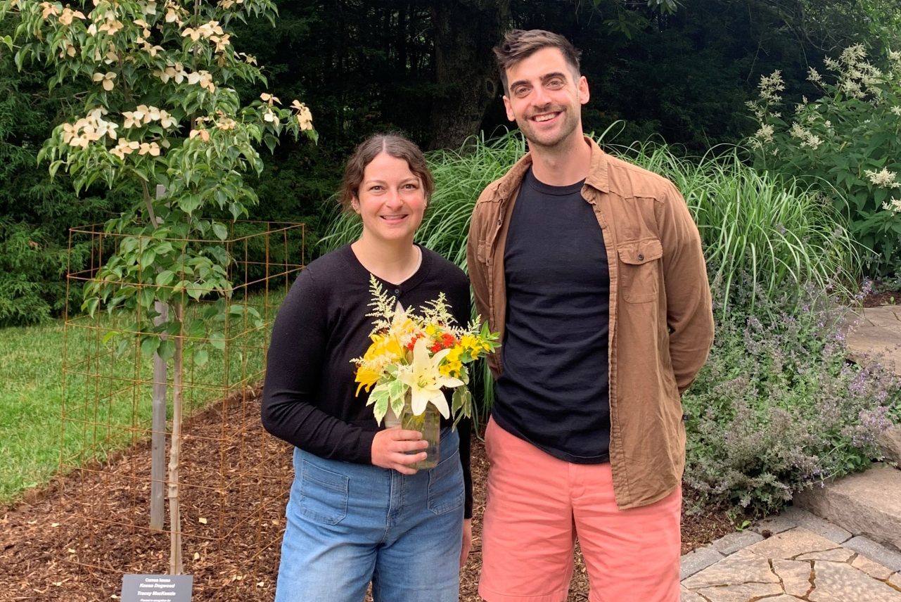 Samantha Bennet holding a bouquet of flowers, standing next to Dr. Paul manning in the Alumni Gardens on campus