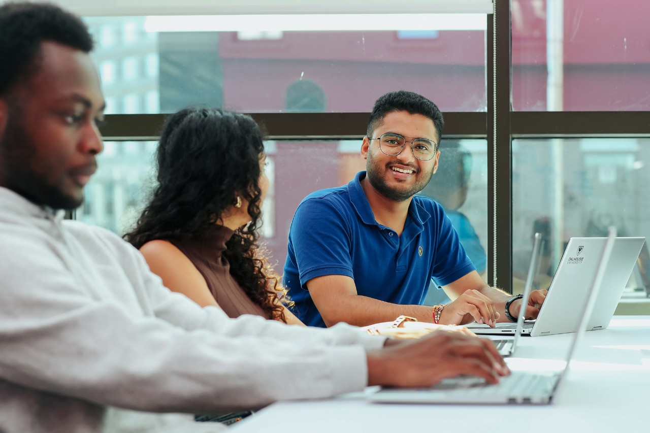 Three students working on laptops in the library.