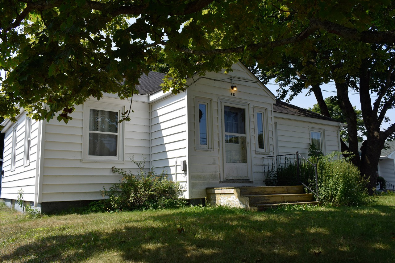 Exterior of white house with tree in the foreground.