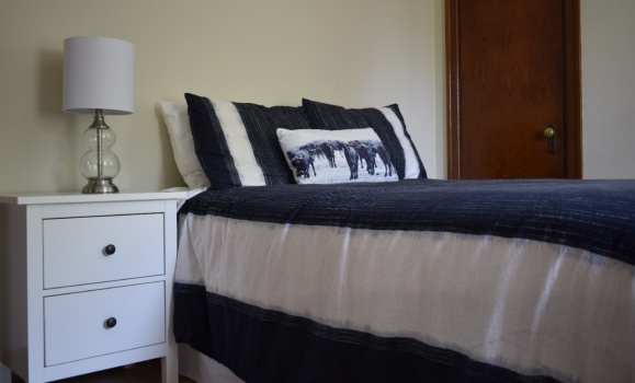 A bed decorated with a navy quilt.