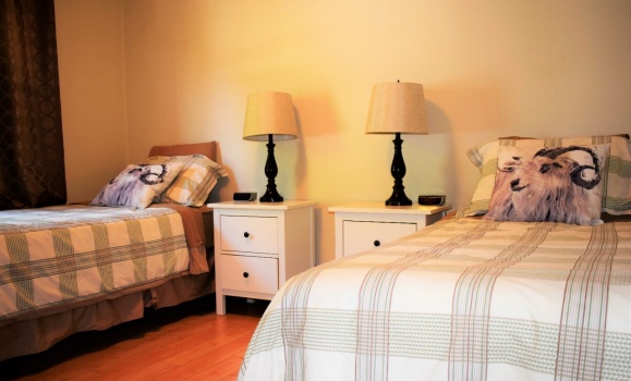 A bedroom with two single beds with tartan quilts and pillows with an image of a ram on them.