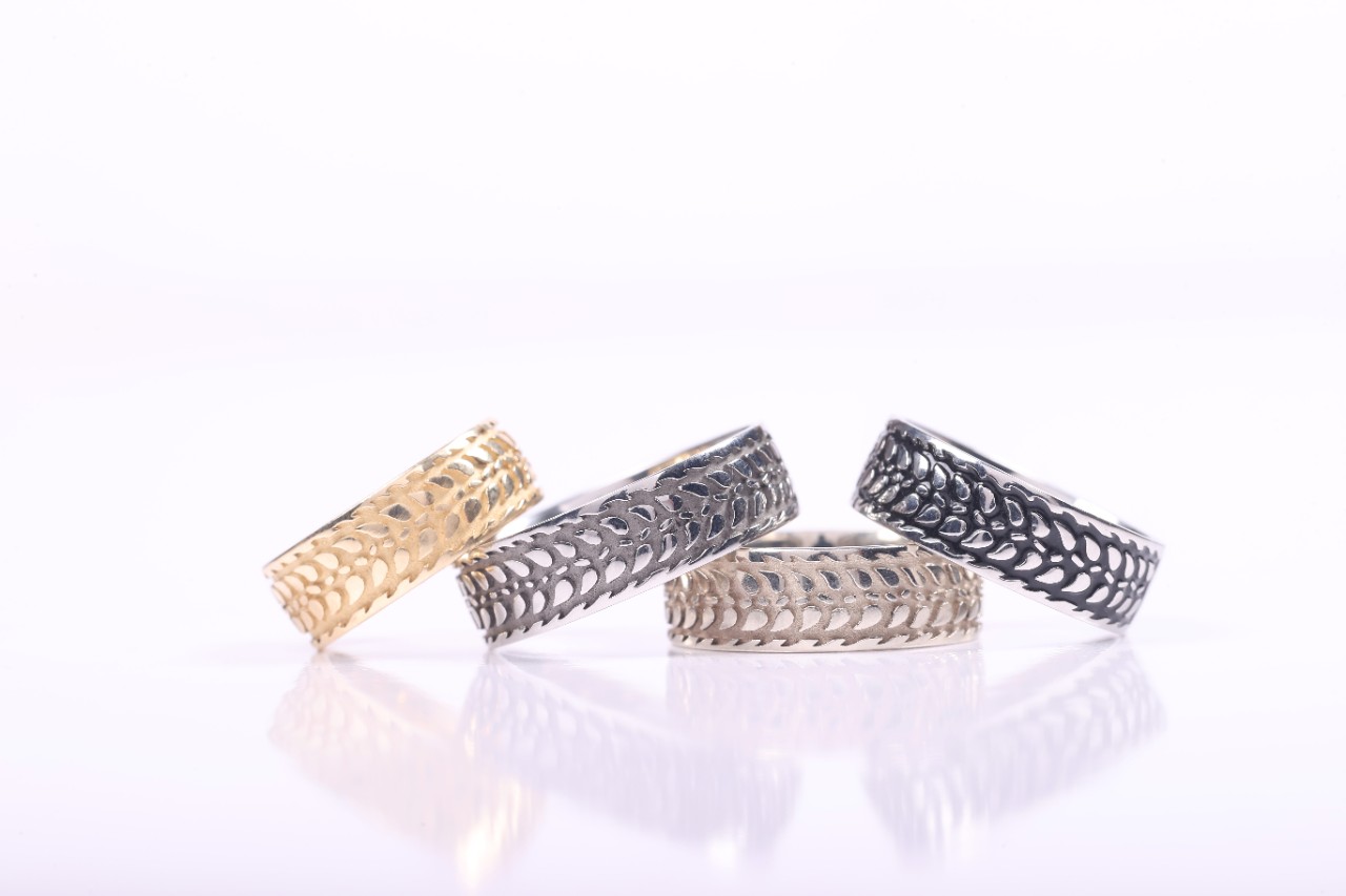 Four Barley Rings in gold, silver and black, silver, and white gold stacked.