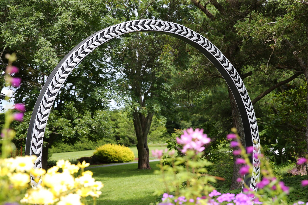 a view of the alumni gardens in summer through the barley arch