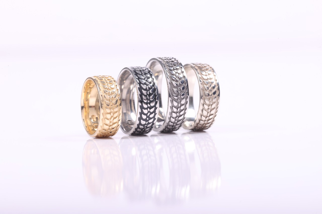 Four Barley Rings in gold, silver and black, silver, and white gold stand on end.