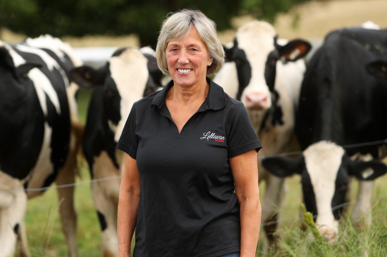 Jeannie Van Dyk standing in a field with cows in the background