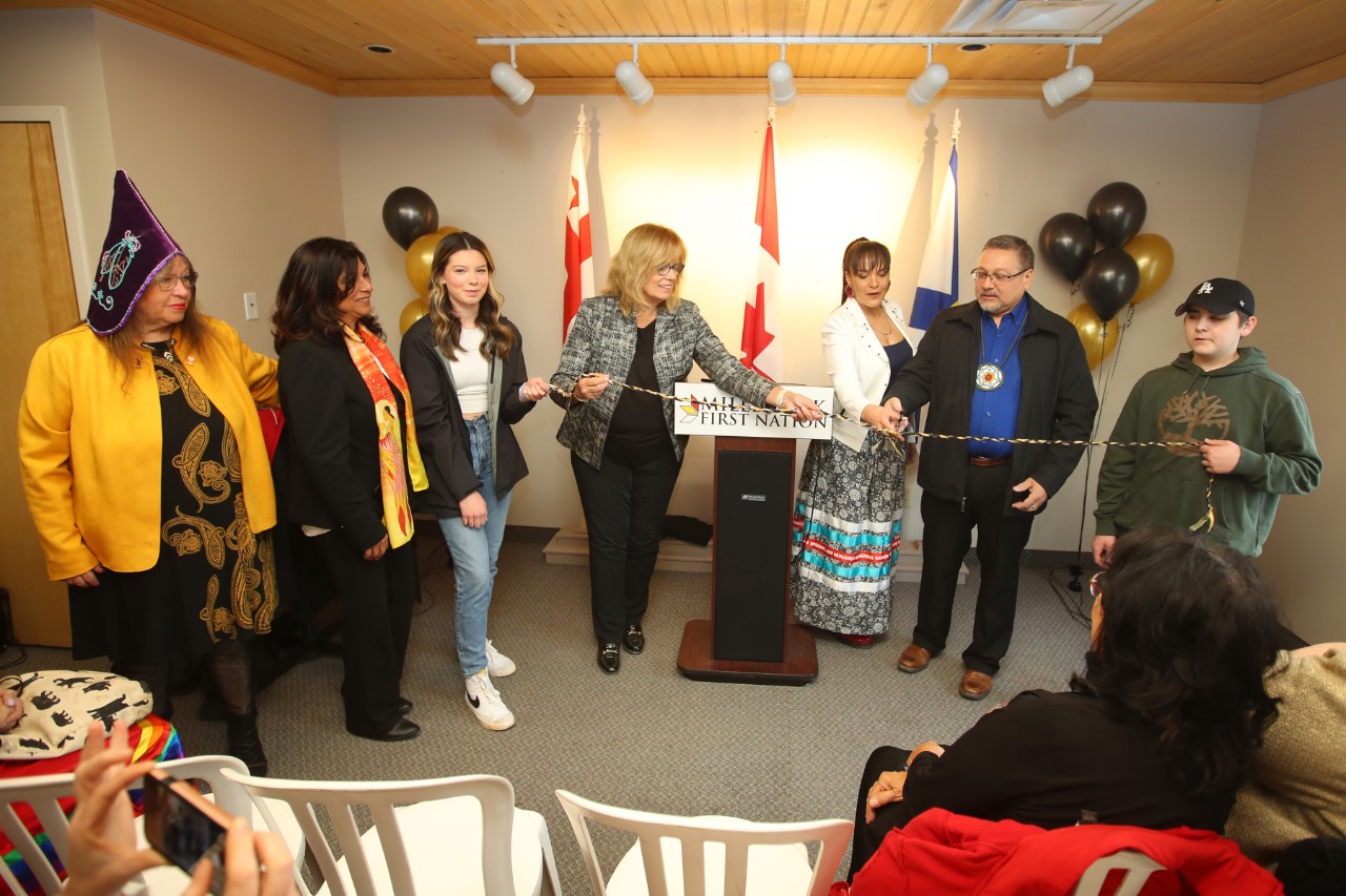 A group of dignitaries in the Millbrook community office cutting a ceremonial ribbon 