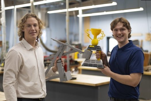 Two AC engineering students holding gauntlet trophies