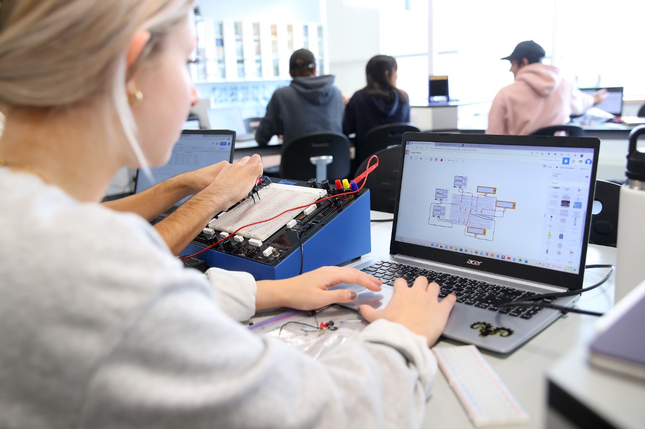 Ag engineering student working on a laptop in a lab with three other students in the background