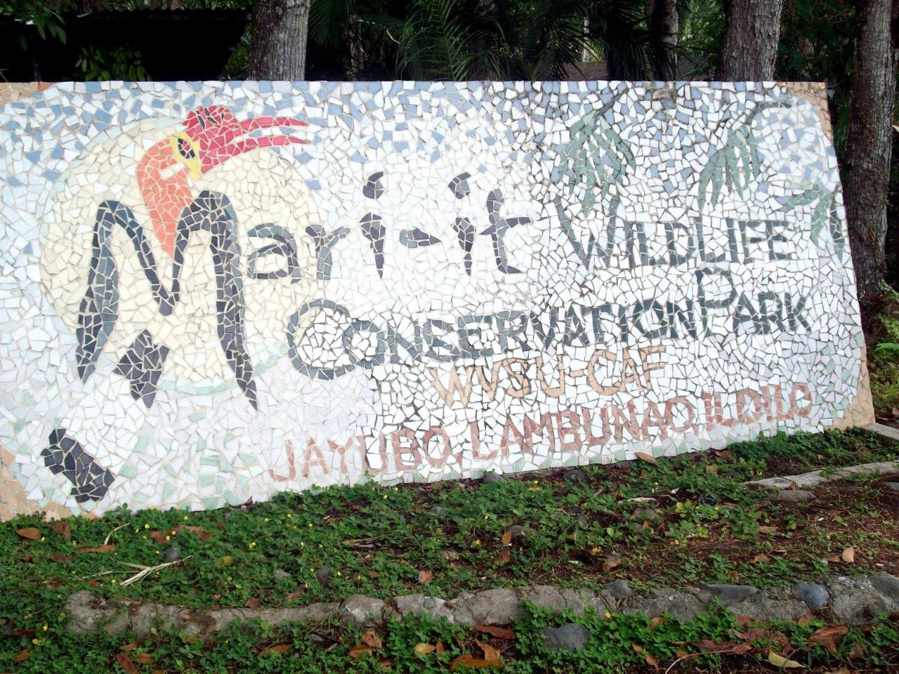 A tile mosaic sign featuring an image of a black and white bird with a red beak that reads "Mari-it Wildlife Convervation Park."
