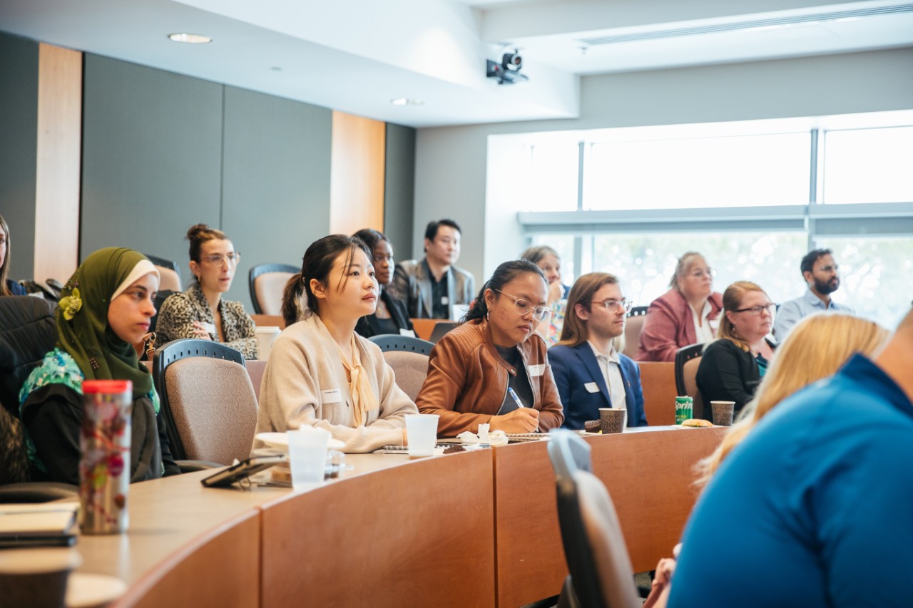 A group of people sitting in a lecture hall and listening to a speaker.