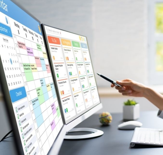 Woman pointing at a computer with a schedule and gannt calendar for her project.