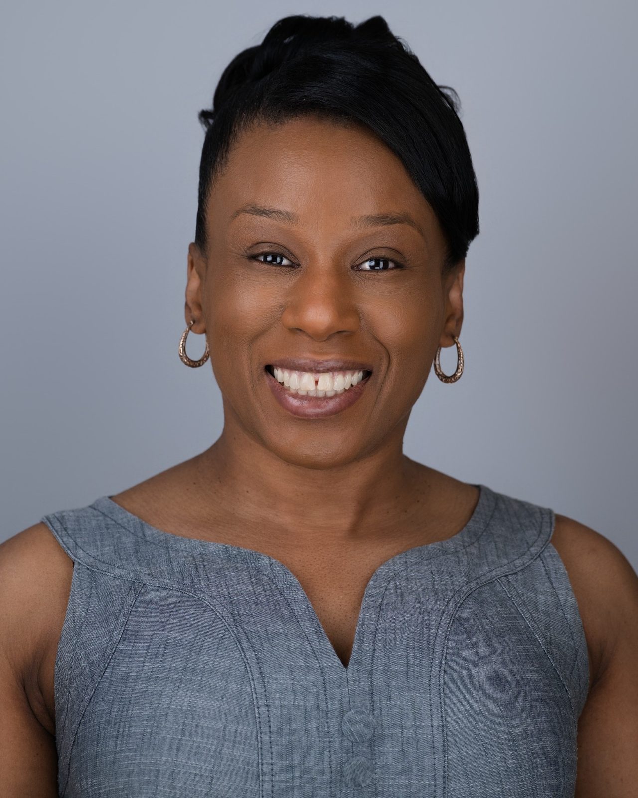A profile picture of a smiling black woman in a grey dress