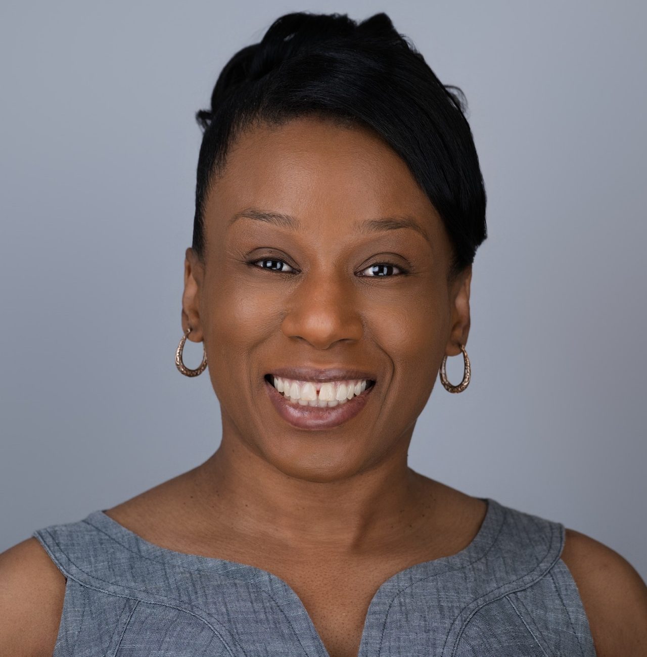 A profile picture of a smiling black woman in a grey dress