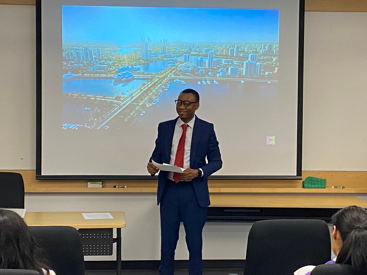 A man leaning on a concrete pillar wearing a hat. 