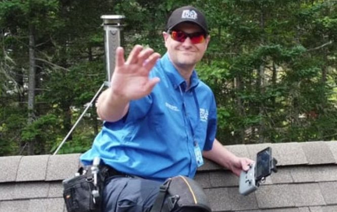 Man on roof with inspection gear waving to the camera