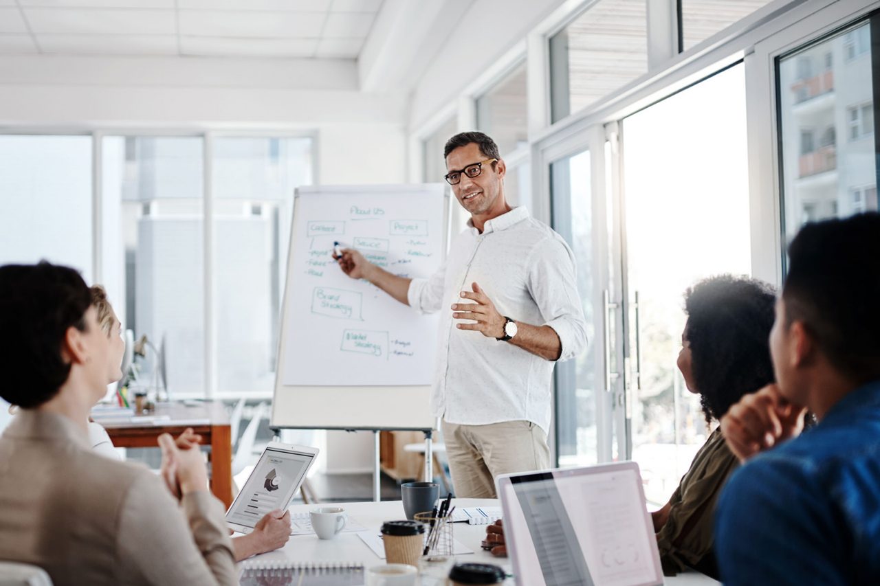 Instructor points to flipchart with a marker as students watch.