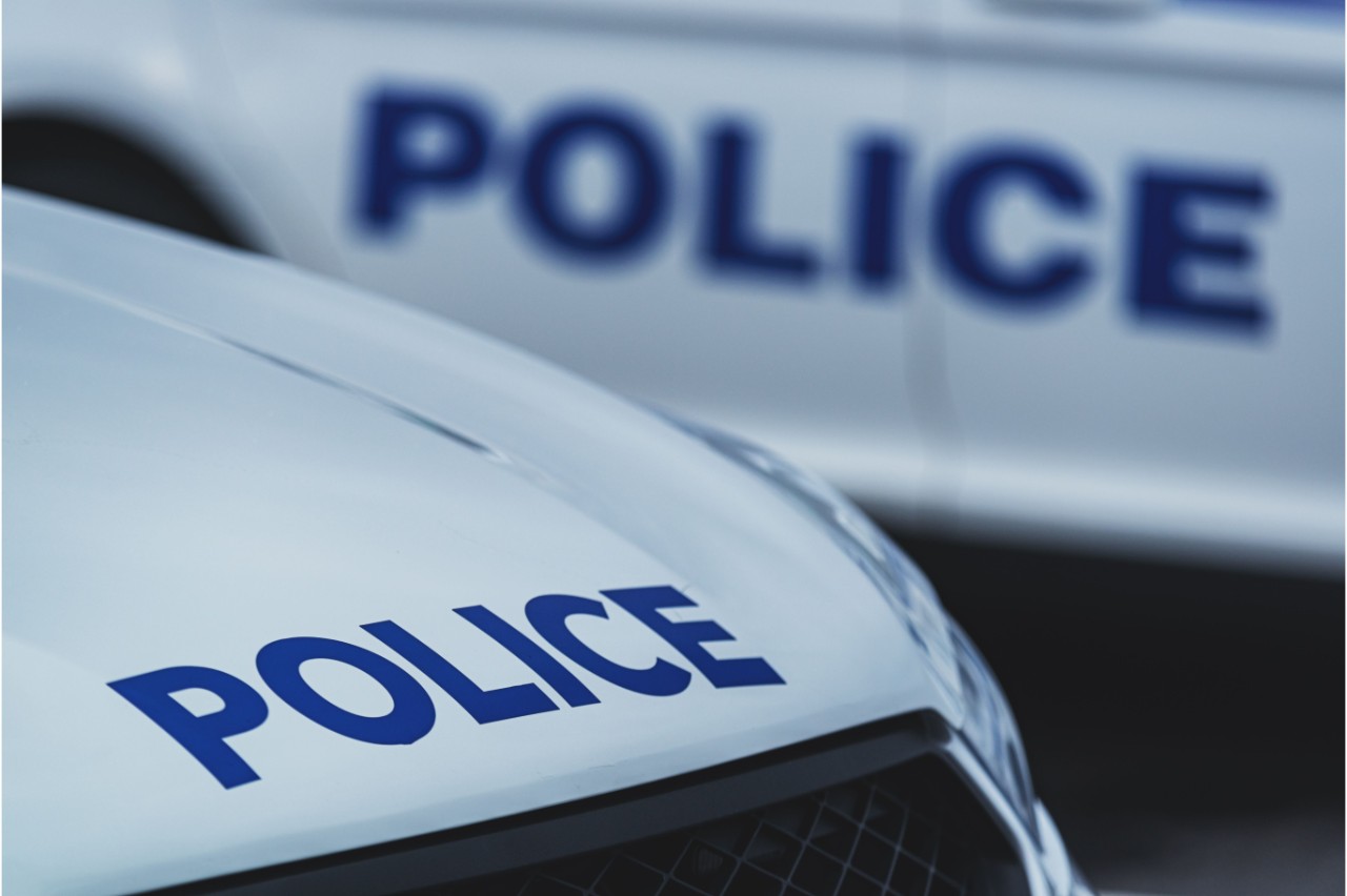 Close-up of the hood of a white police car, with "Police" in blue text.