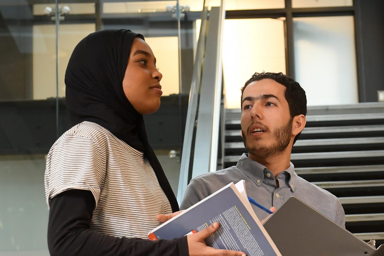 Two students talking with open textbooks