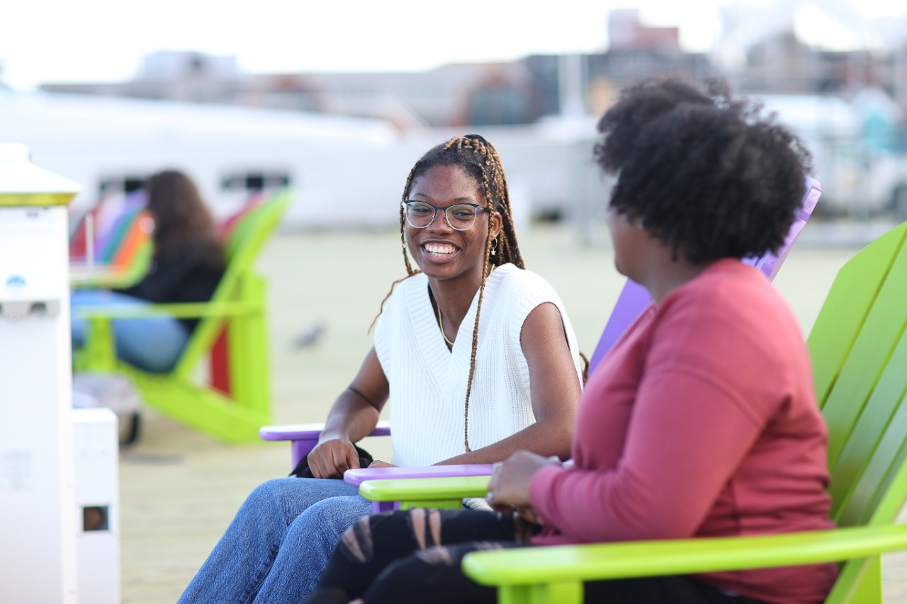 Two students in bright green chairs on the Halifax waterfront.