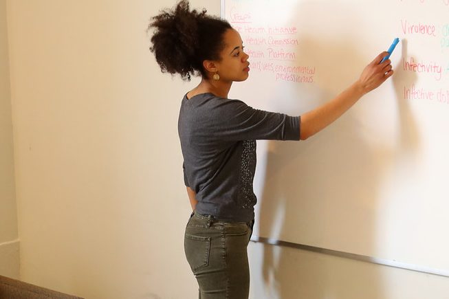 Group of students studying together while one writes on a white board