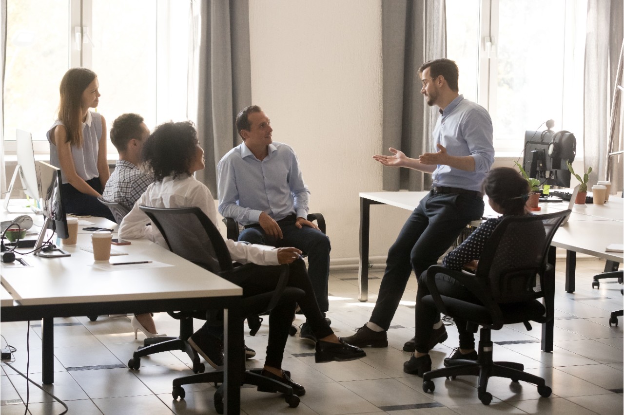 A man sitting on a work table talking to other people