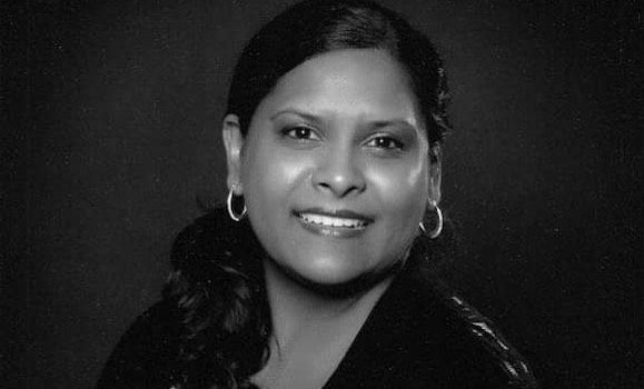 Black and white headshot of Denise smiling at the camera.
