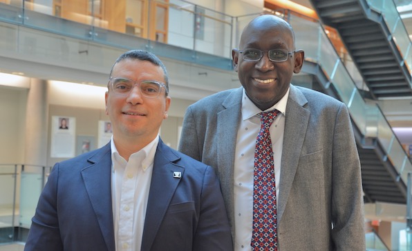 Drs. Attig and Sy, dressed in suits, pose together, smiling.