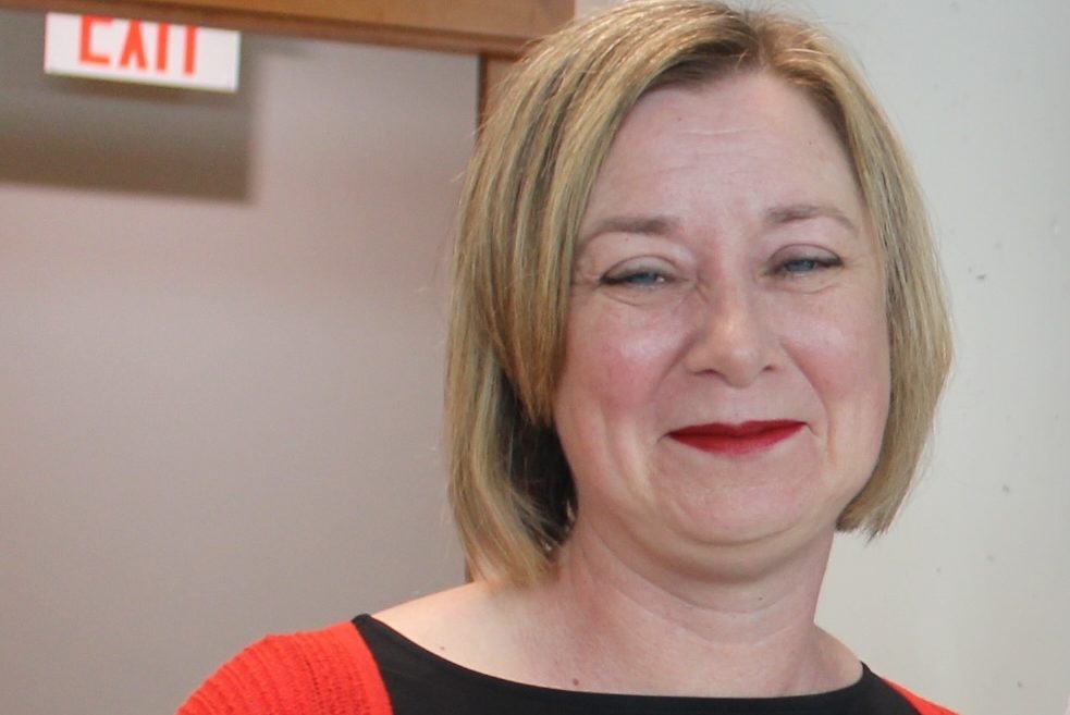 Headshot of Stacy wearing a red shirt and smiling. 