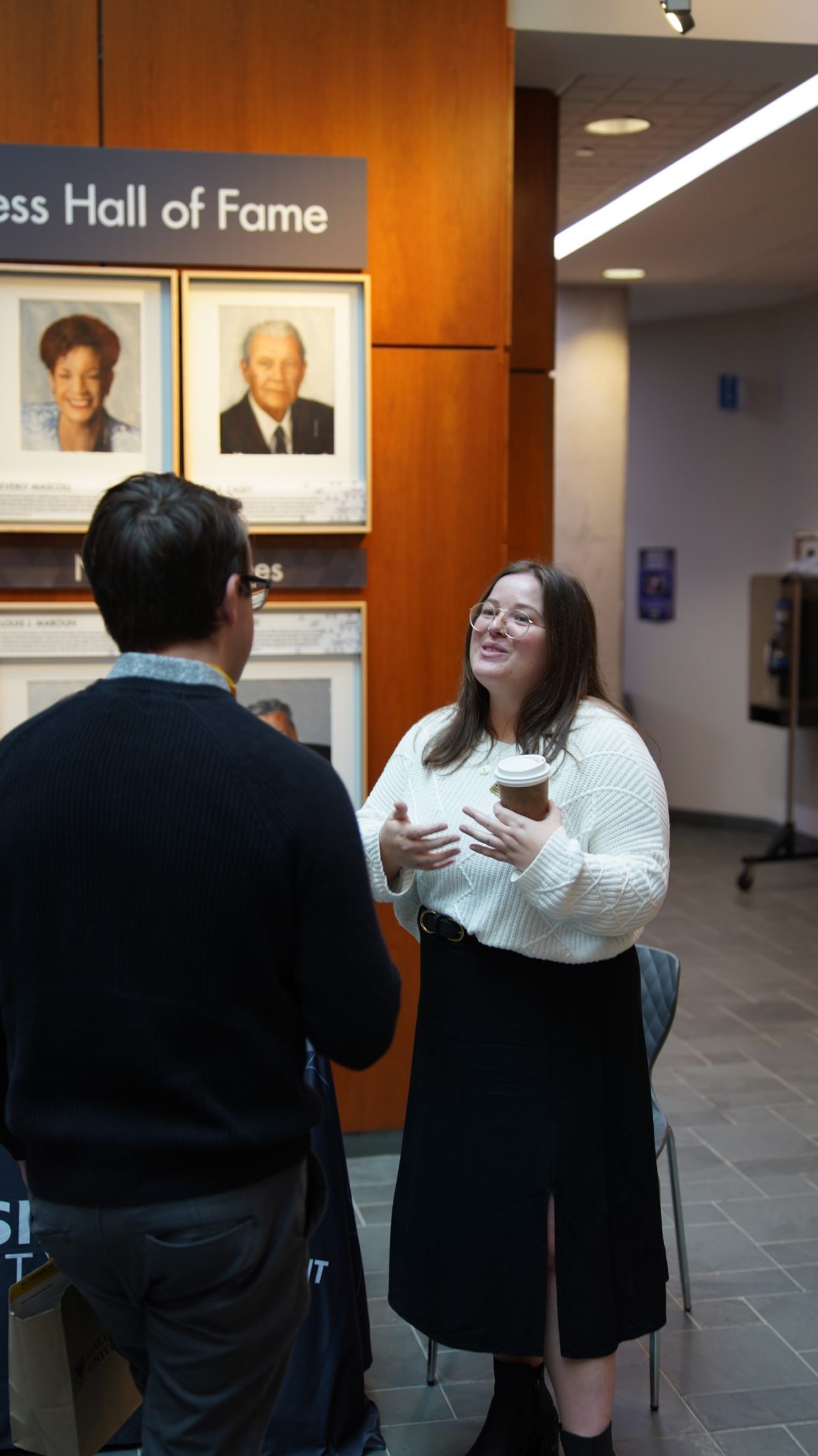 Michelle smiling, speaking to student, in lobby of the Rowe. 