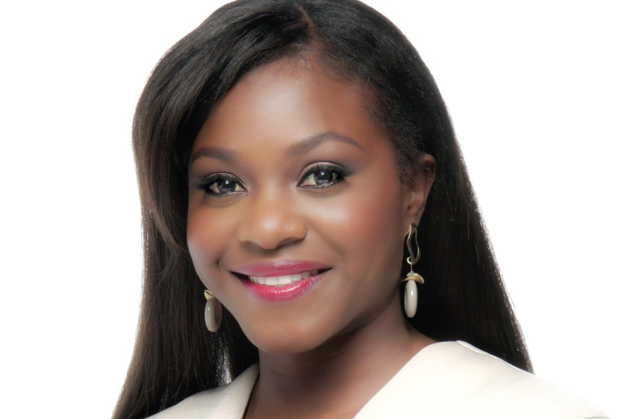 A portrait of Kenisha dressed in a white suit and smiling.  