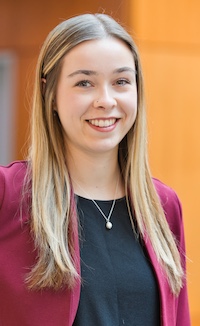 MPA student Hannah smiles at camera wearing a red jacket and black shirt.