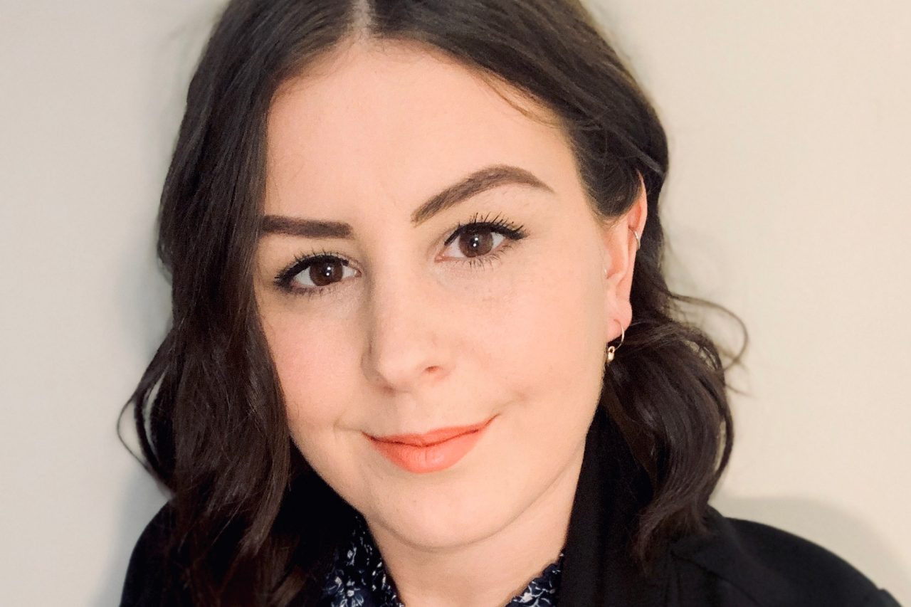 MPA student Blair smiles at camera wearing black blazer and floral shirt 