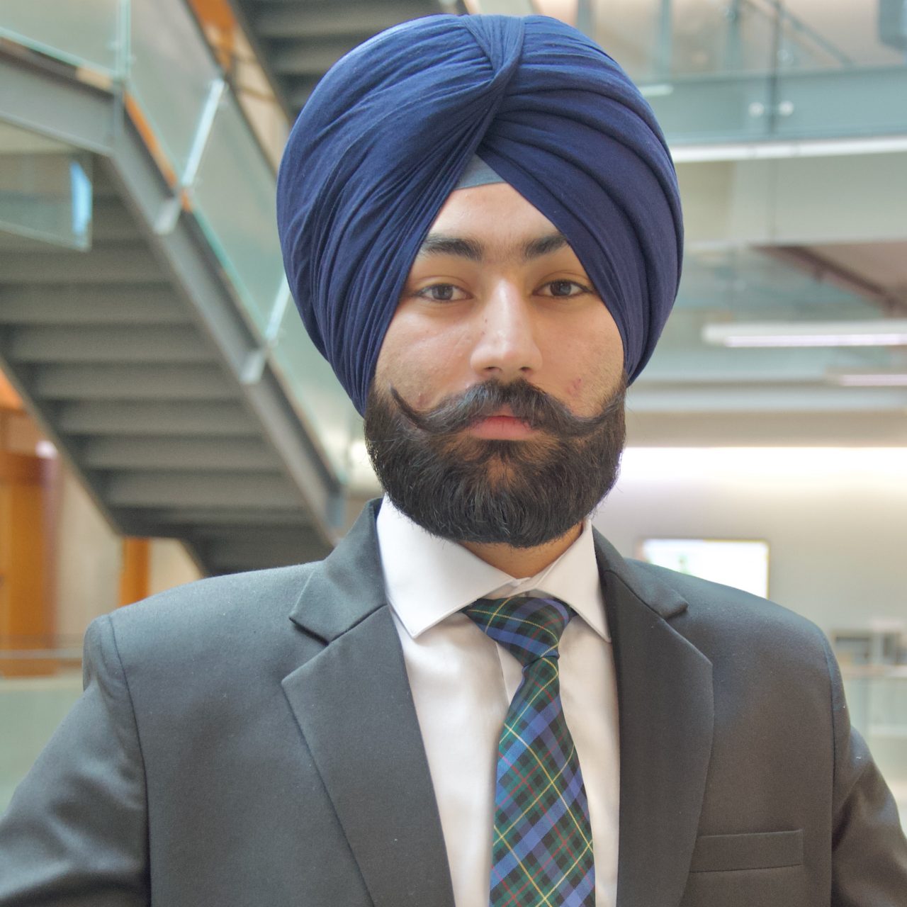 Amrit, in business wear and a turban, poses confidently.  