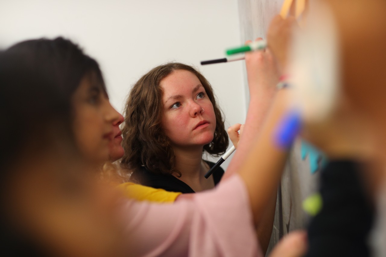 group of students writing on sticky notes stuck to the wall