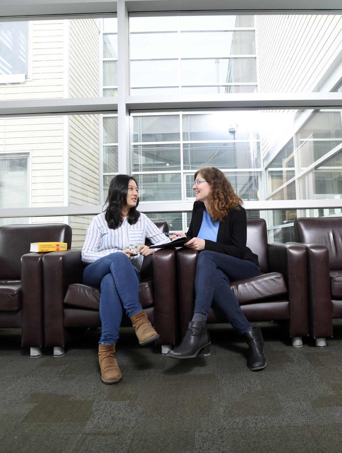 Student and professor sitting in chairs having a discussion