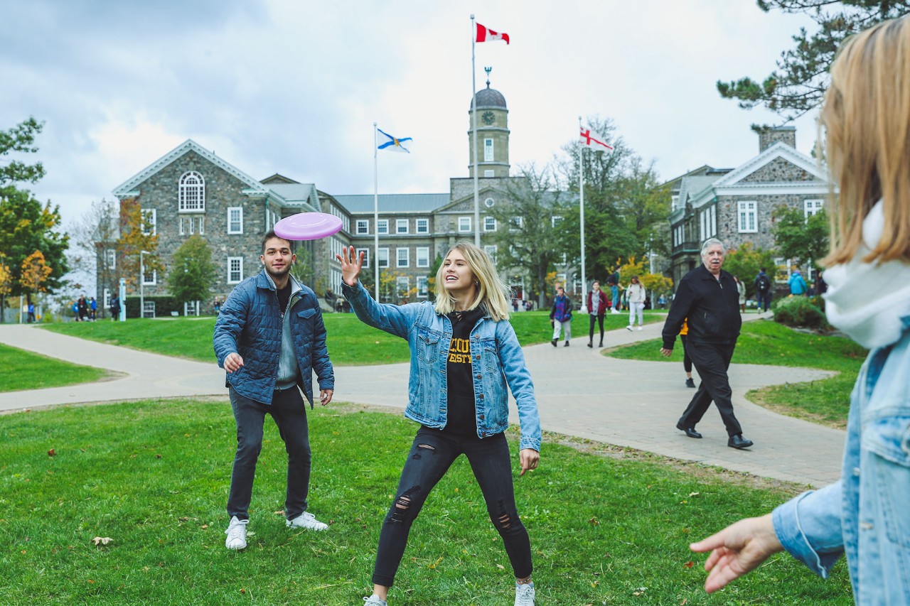 Students on quad playing frisbee in front of the Henry Hicks Building