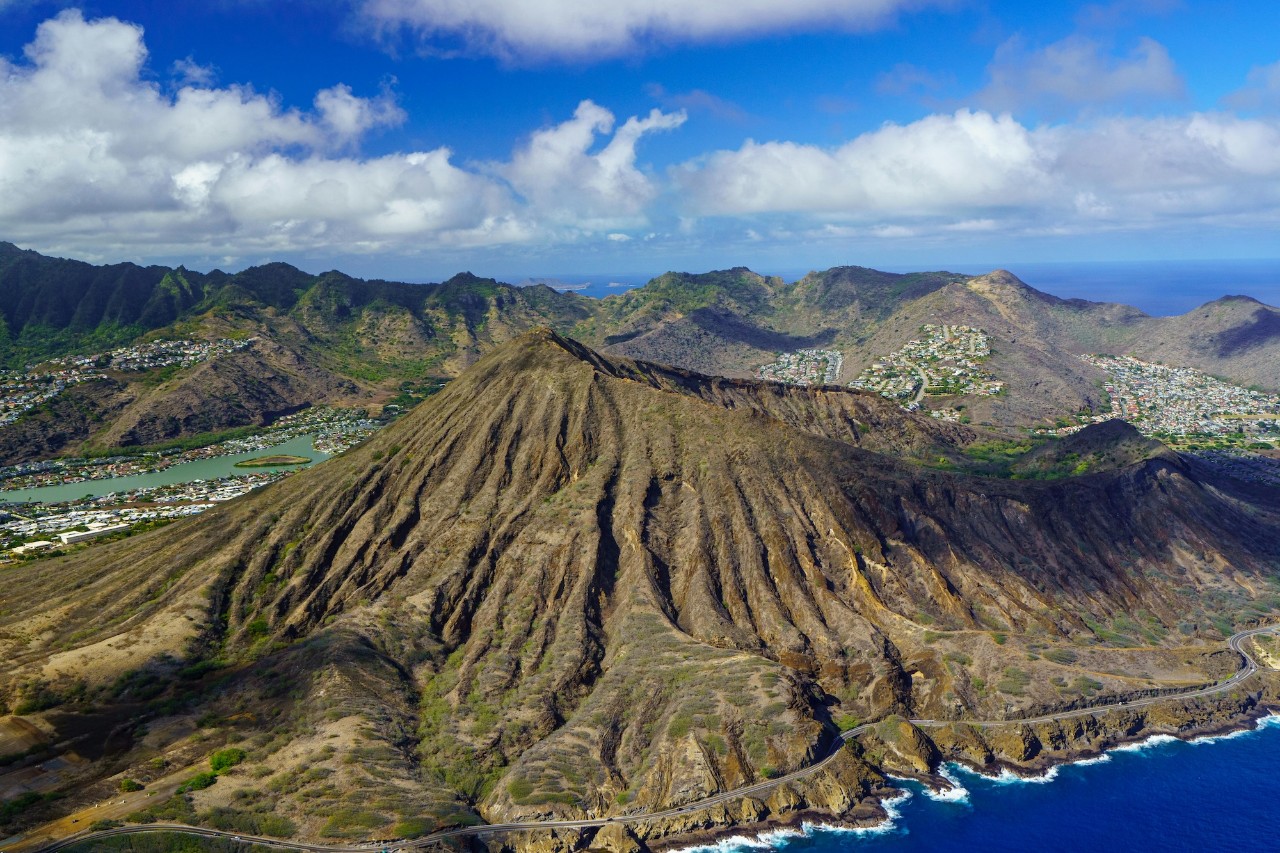Large brown and green hills rise up from blue tropical ocean waters around them.