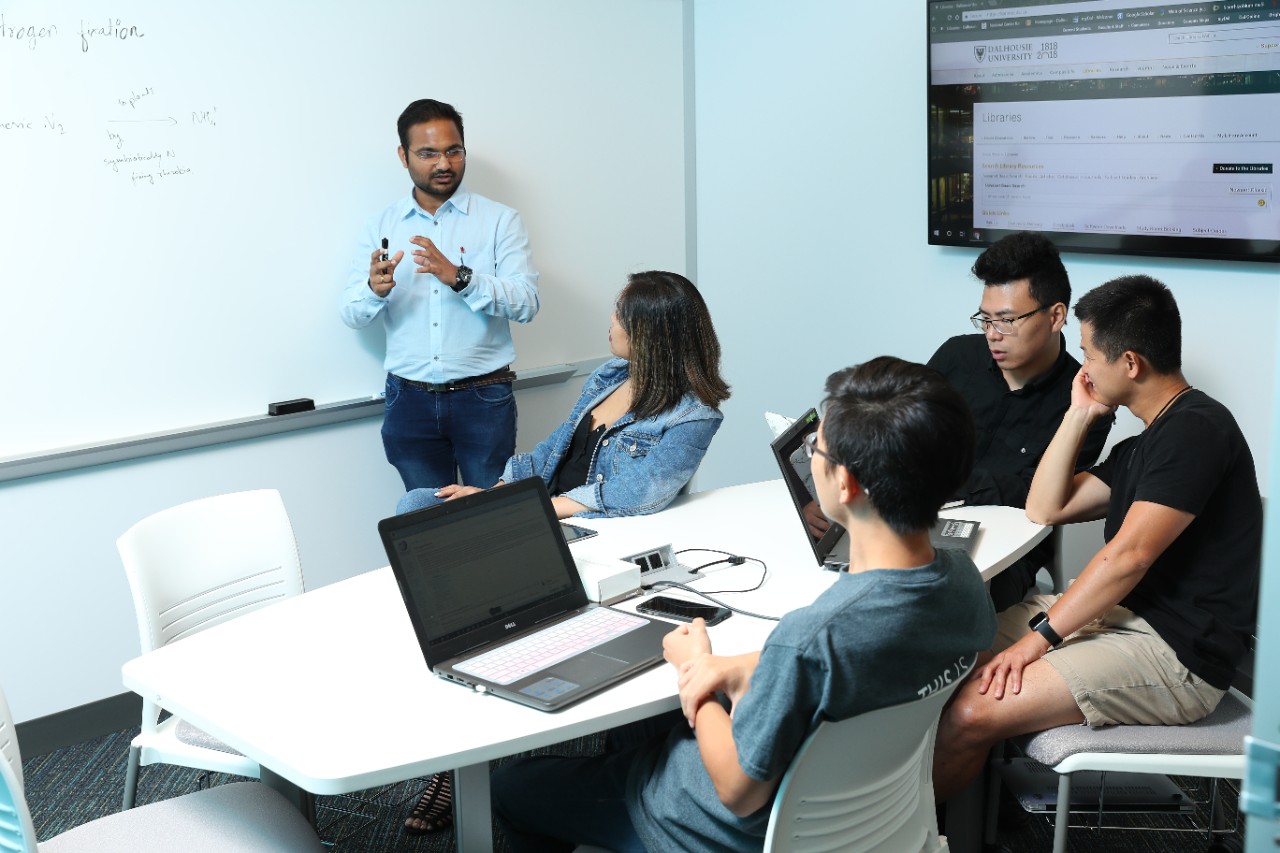 Faculty member teaching in front of a small group of students.