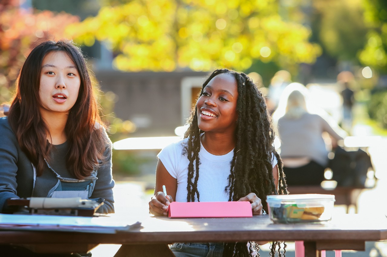 Two people looking at one laptop inside the student learning commons